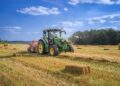 Trator em campo agrícola ao entardecer, com display digital no painel exibindo dados de operação.