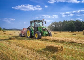 Trator em campo agrícola ao entardecer, com display digital no painel exibindo dados de operação.