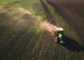 trator verde e branco em campo de grama verde durante o dia